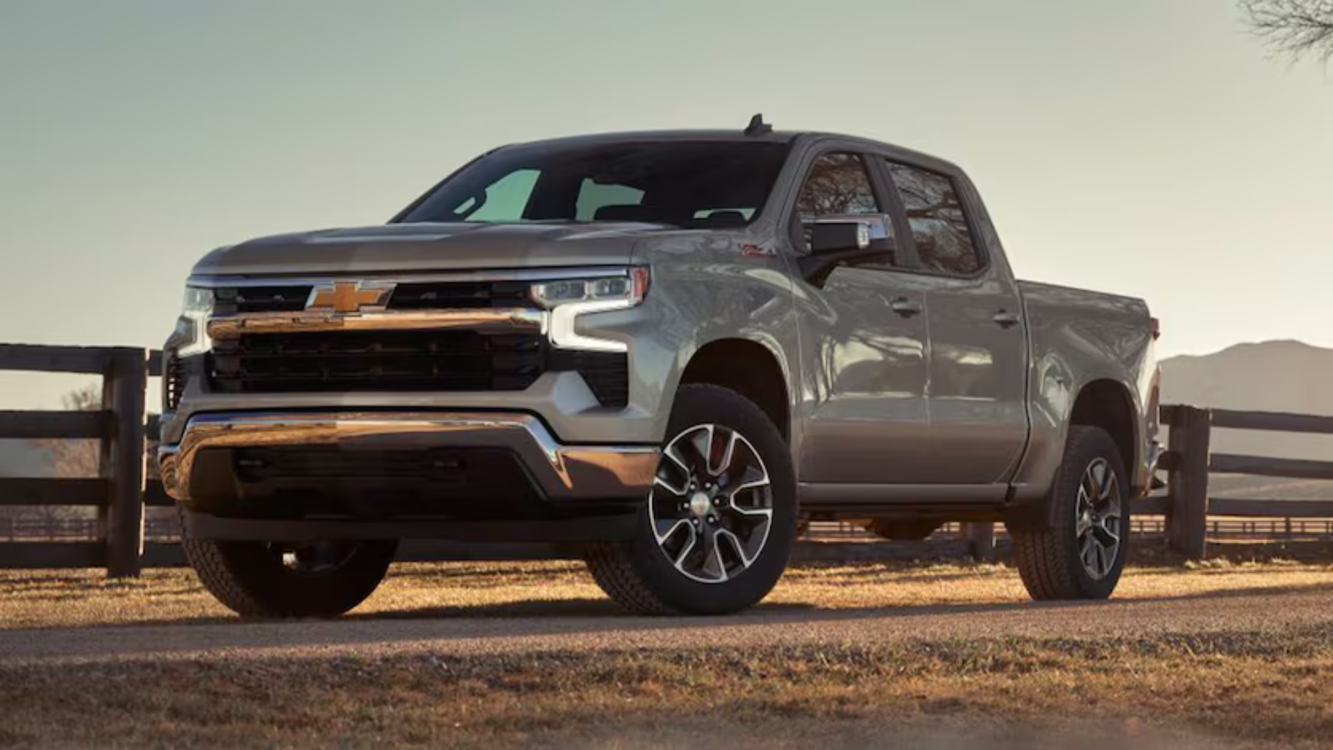 Silver Chevrolet Silverado pickup truck parked on a ranch-style road at sunset, showcasing rugged design and capability, available at Platinum Chevrolet in Santa Rosa.
